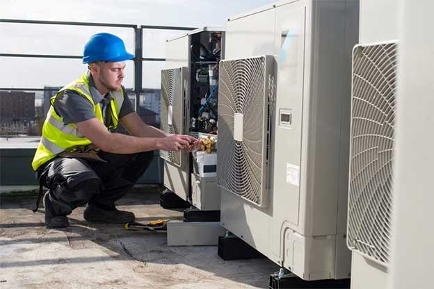 A commercial HVAC technician repairing an industrial air conditioning unit.